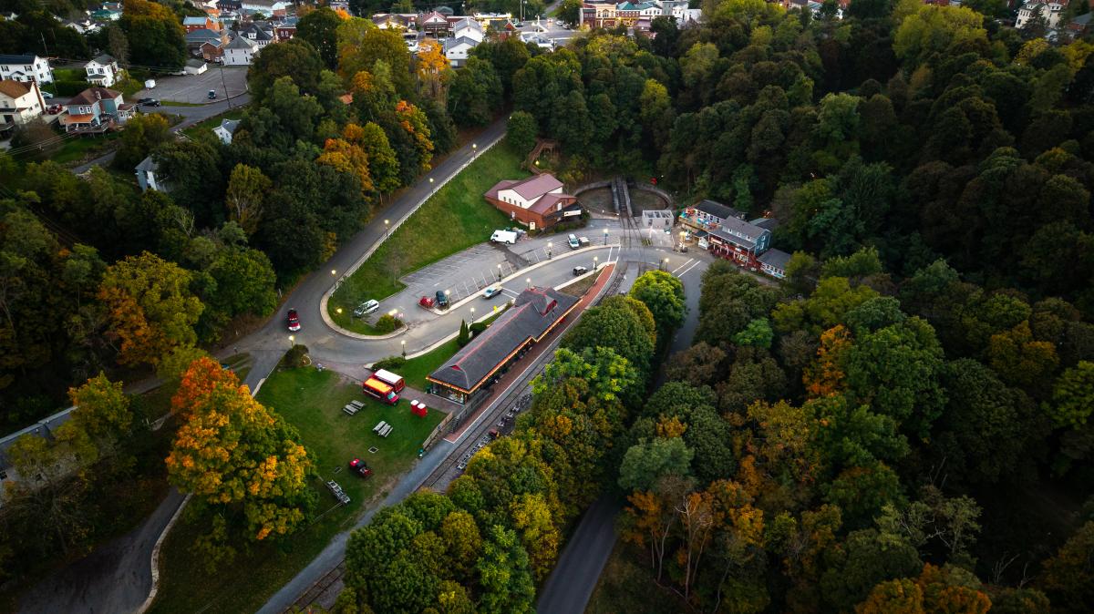 An aerial view of the Frostburg Depot space in early fall, overlooking train tracks the Depot building and winding roads.