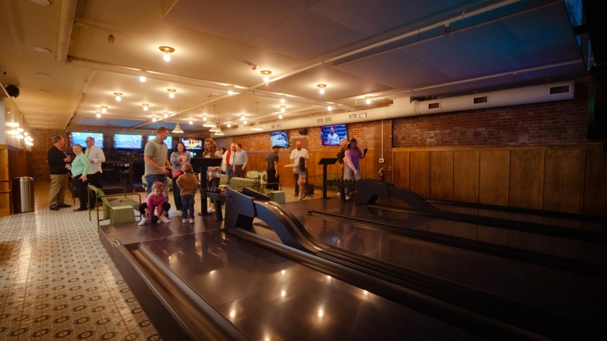 Little girl getting ready to roll the duckpin bowling ball down the lane in Social on Main in Downtown Elizabethtown