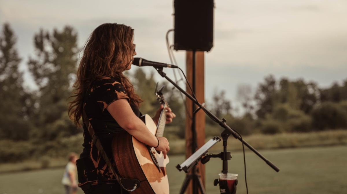 Woman with guitar singing into microphone