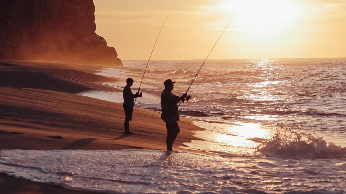 Two mean on the beach in Los Cabos at sunset fishing