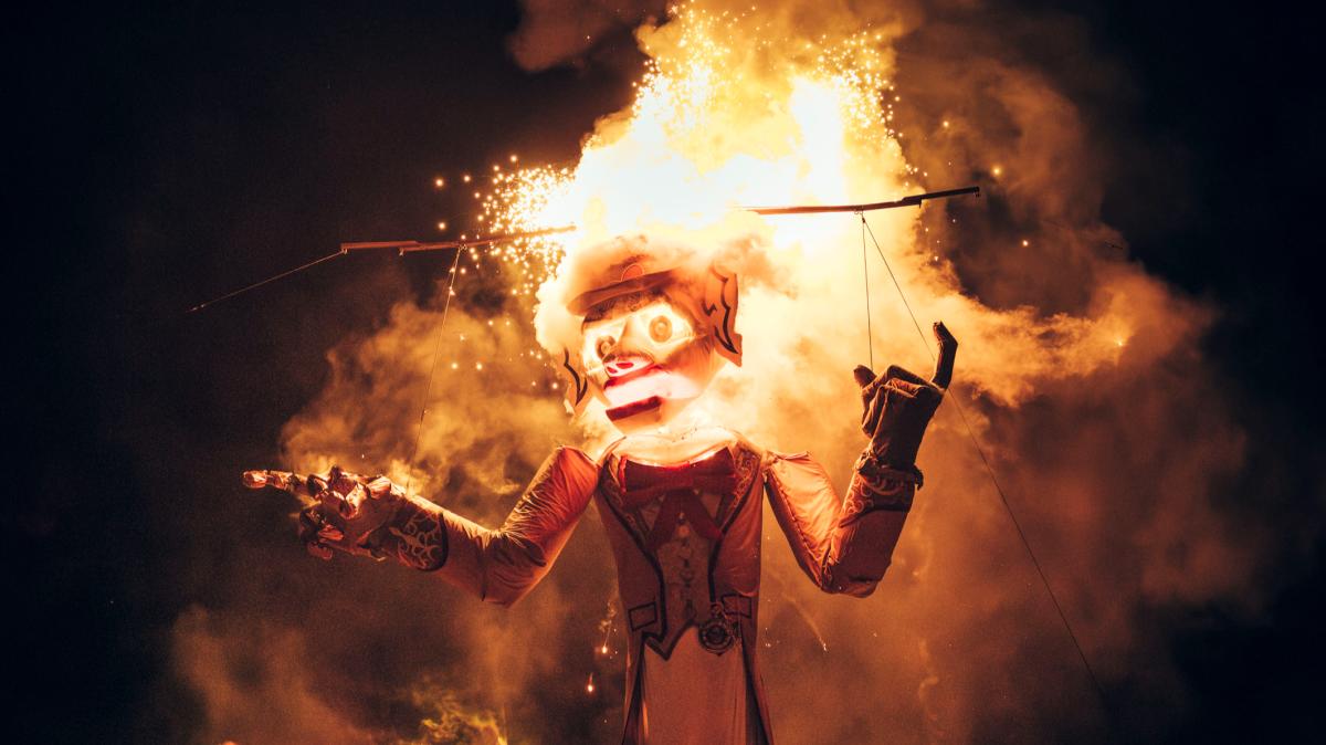A towering effigy of Zozobra, engulfed in flames, stands amid a dark night.