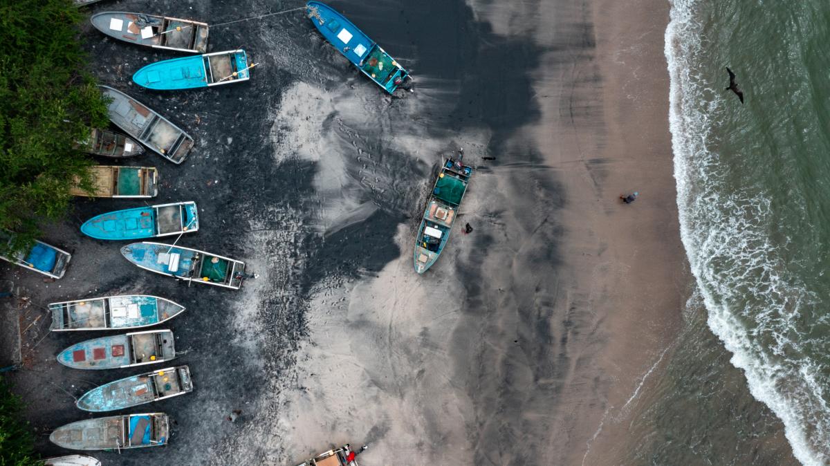 Vista de la arena negra en playa de Gorgona, se pueden ver algunos coloridos botes de pesca