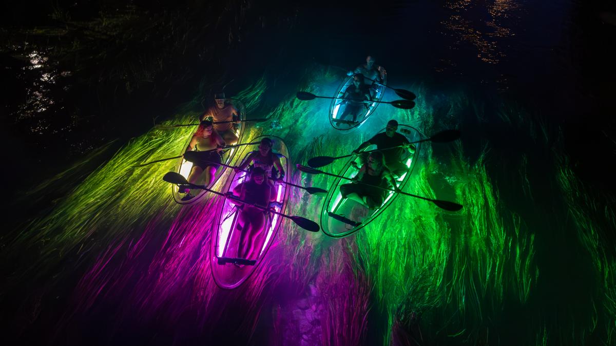 A group take a glow tour on the San Marcos River