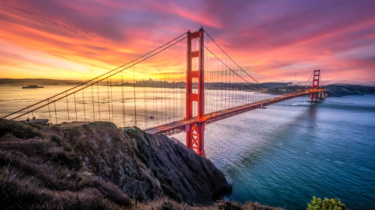 The sun sets over San Francisco with a beautiful view of the Golden Gate Bridge in the forefront.