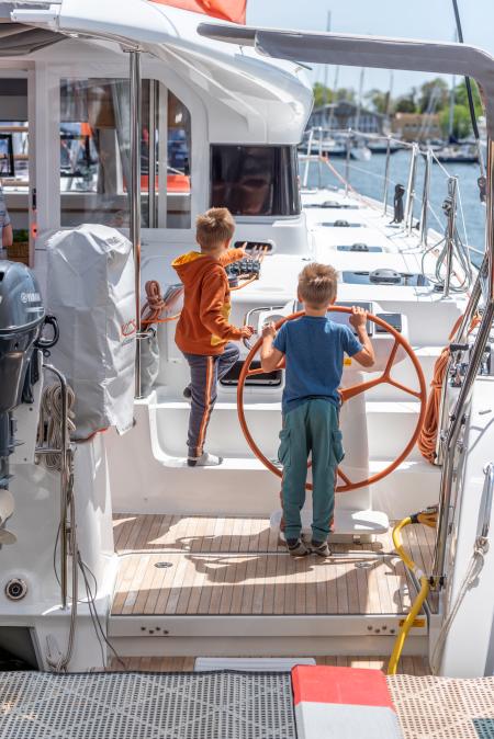 two young boys helming the cockpit of a sailboat