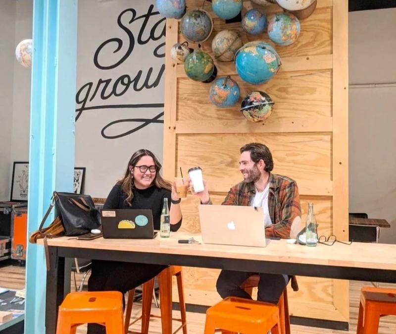 Two people sit at a table in Humble coffee working on laptops