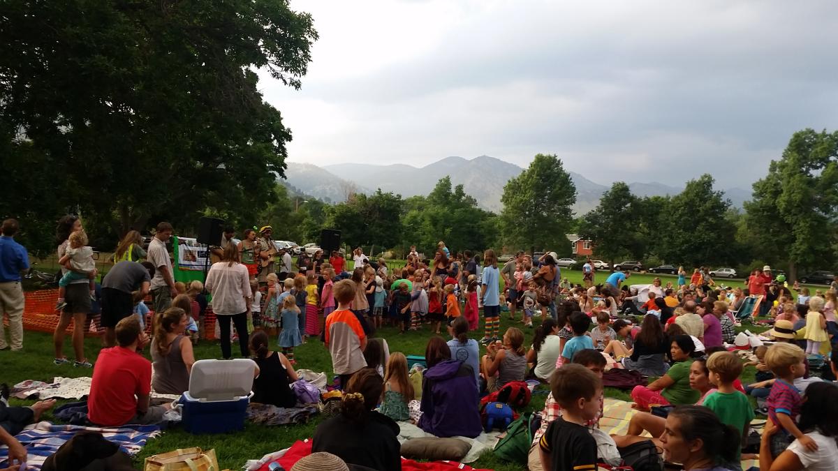 People gathered on the grass listening to a band at the Meadow Music Concert