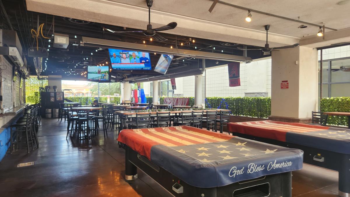 patio view with tvs playing sports games, picnic tables and pool tables