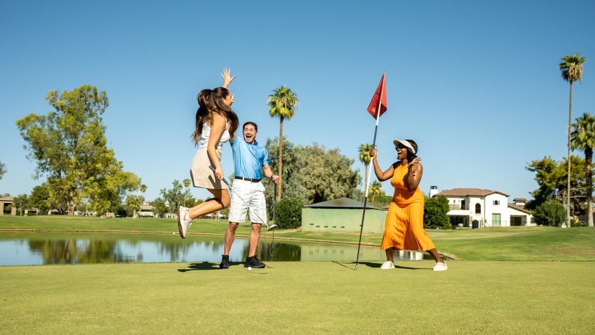 Group jumping and cheering at golfer who putted golf ball into the hole on the San Marcos Golf Course.