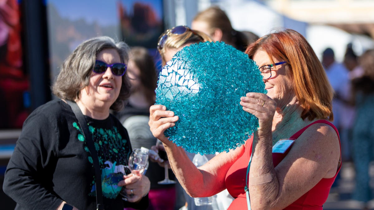 two ladies admiring a glass plate at an outdoor festival