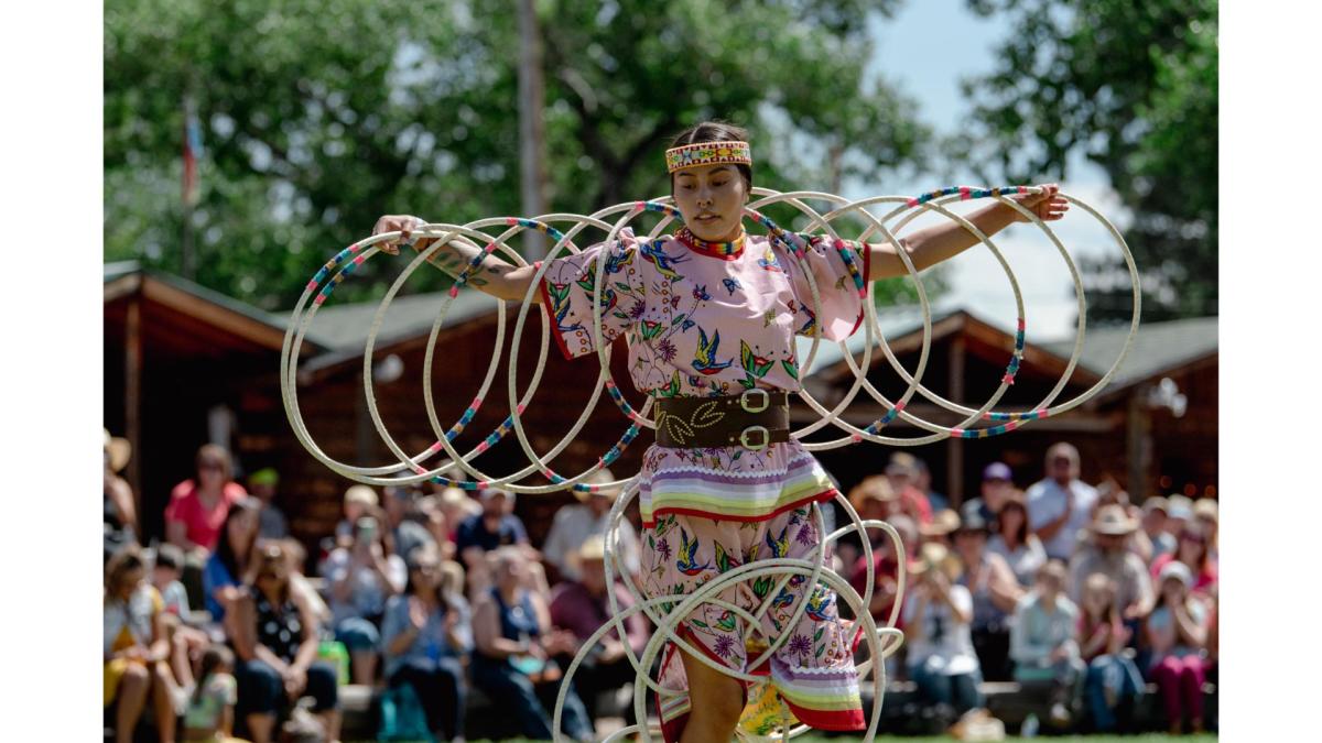 Female hoop dancer performing a traditional storytelling routine with multiple hoops at Morning Star American Indian Village, watched by families and visitors.