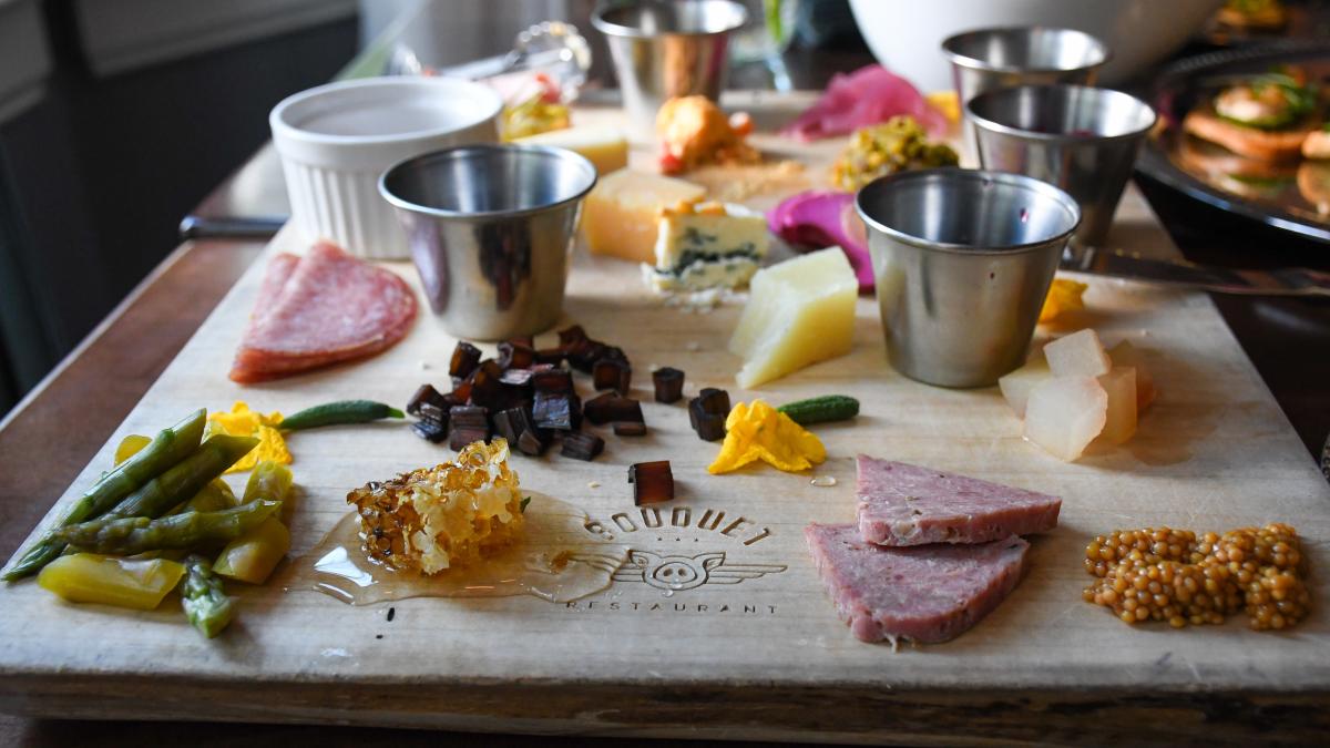 A charcuterie board of cheeses, meats, pickles and dried fruits