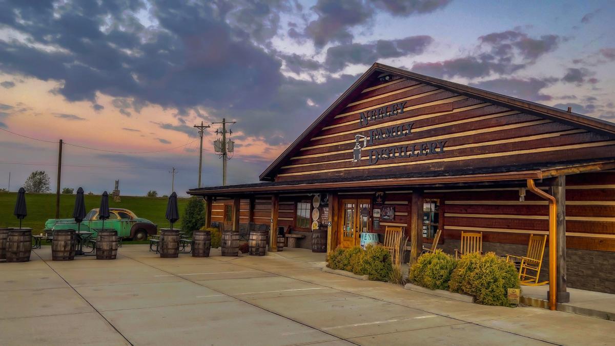 Exterior photo of the Neeley Family Distillery with a green vintage car in front at sunset