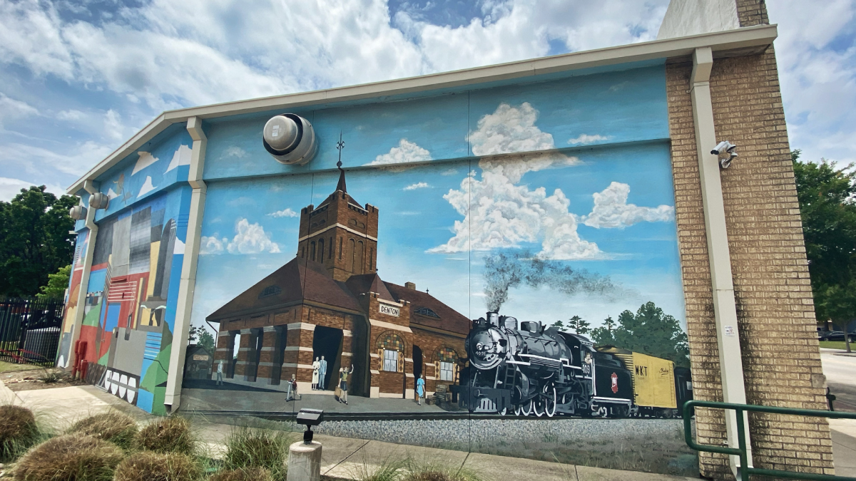 A mural on the side of a building of a train station