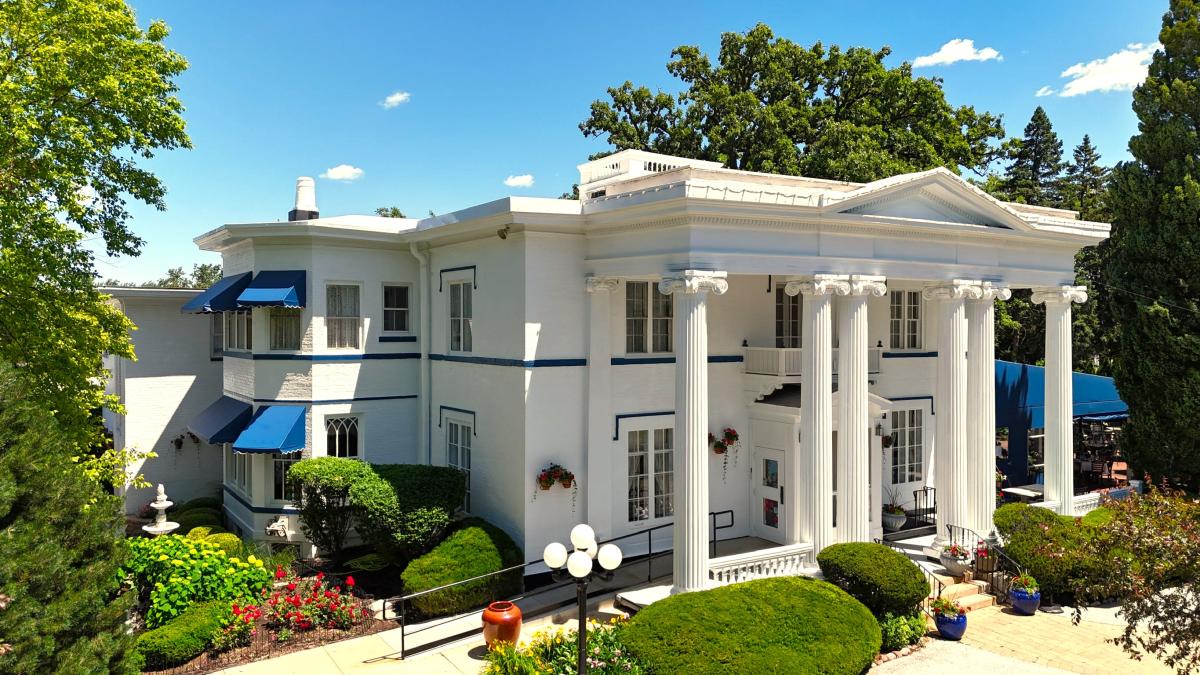 a large white mansion with greenery in the front