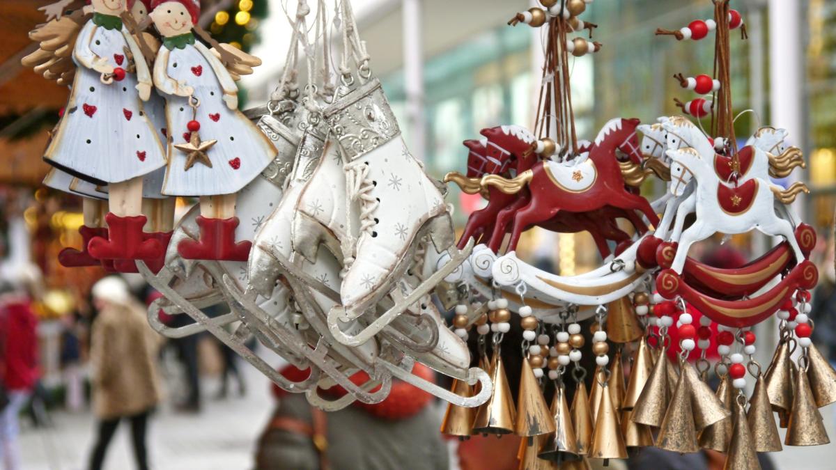 White and red ornaments of angles, ice skates, and rocking horses hanging at a festive Christmas market.