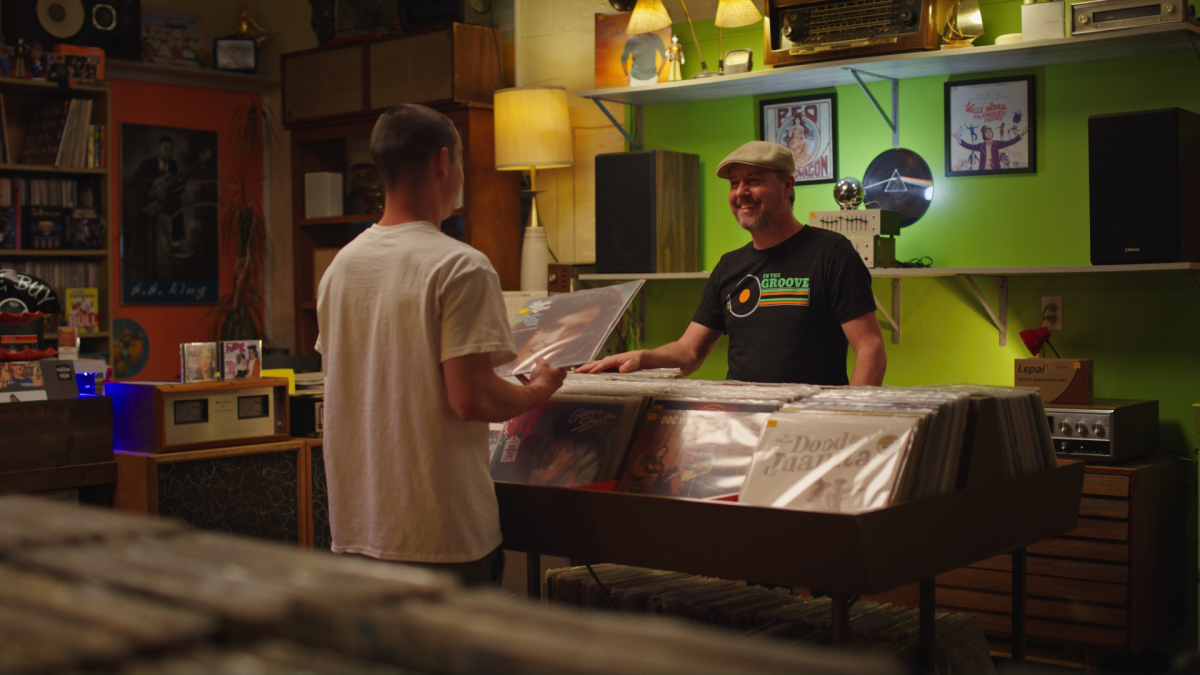 customer and employee talking over bin full of vinyl records