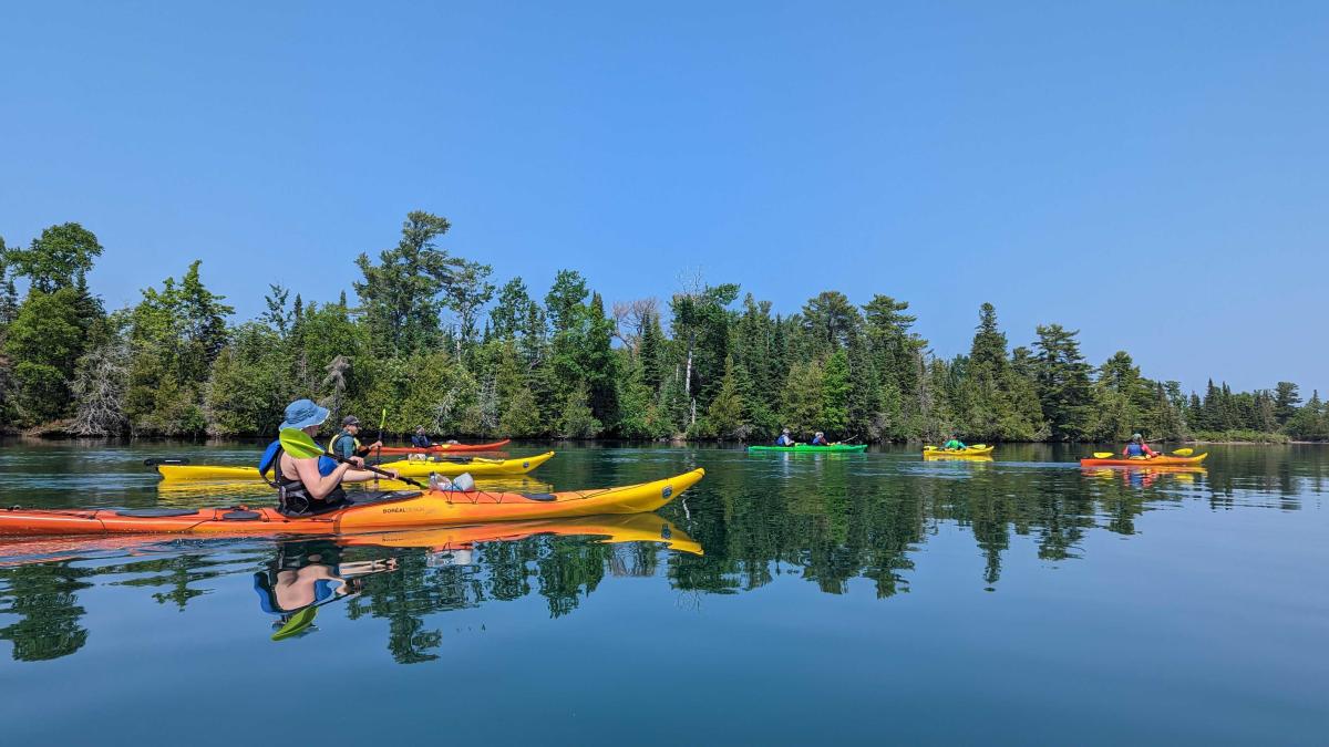 Kayakers paddle on glass calm waters of Copper Harbor