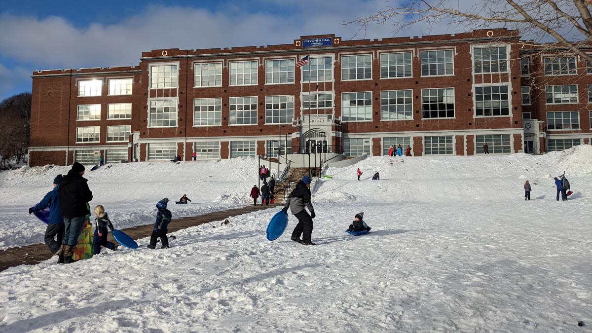 Many people sled on Quincy Green Hill on a sunny winter day.