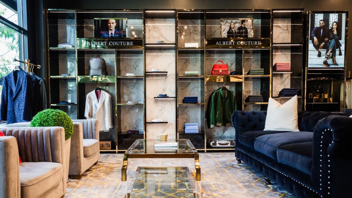 Men's clothing store with sport coats and shirts hanging on the wall, includes a sitting area with couches and coffee table