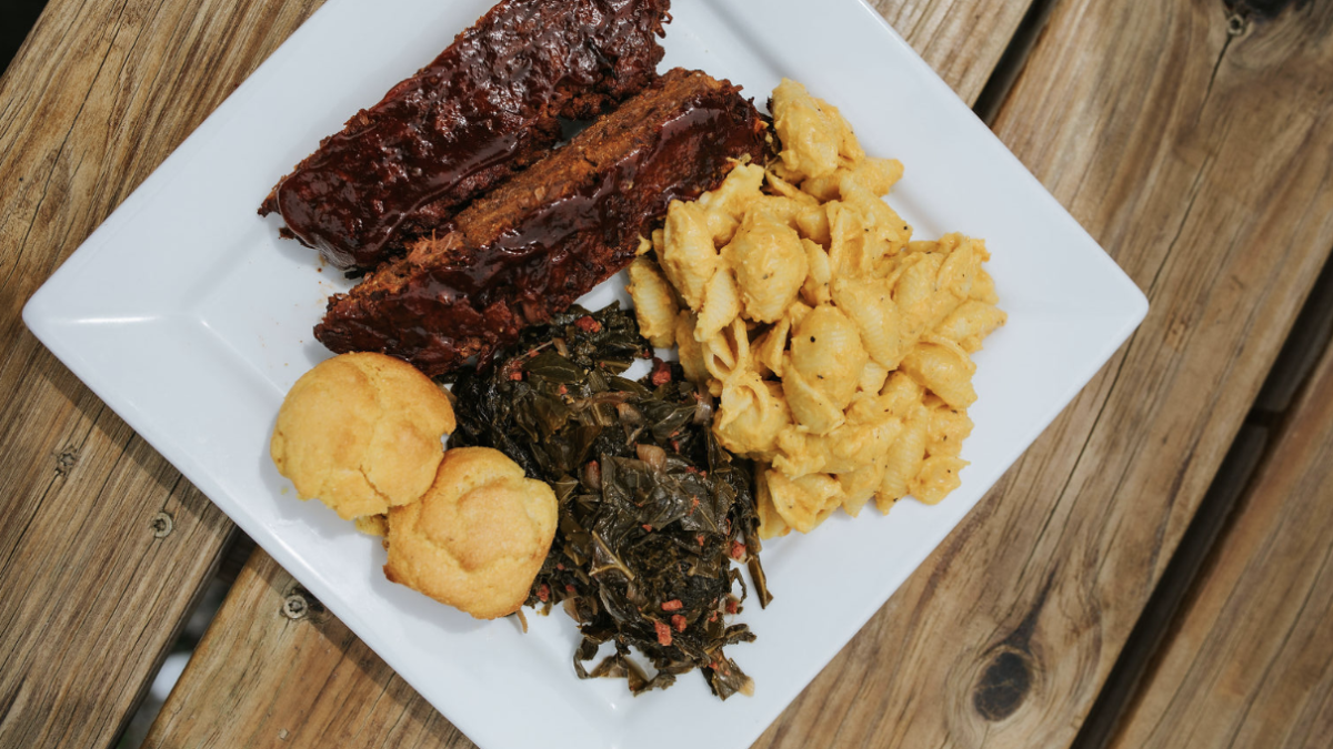 Plate of food with vegan mac n cheese, greens, rolls and BBQ
