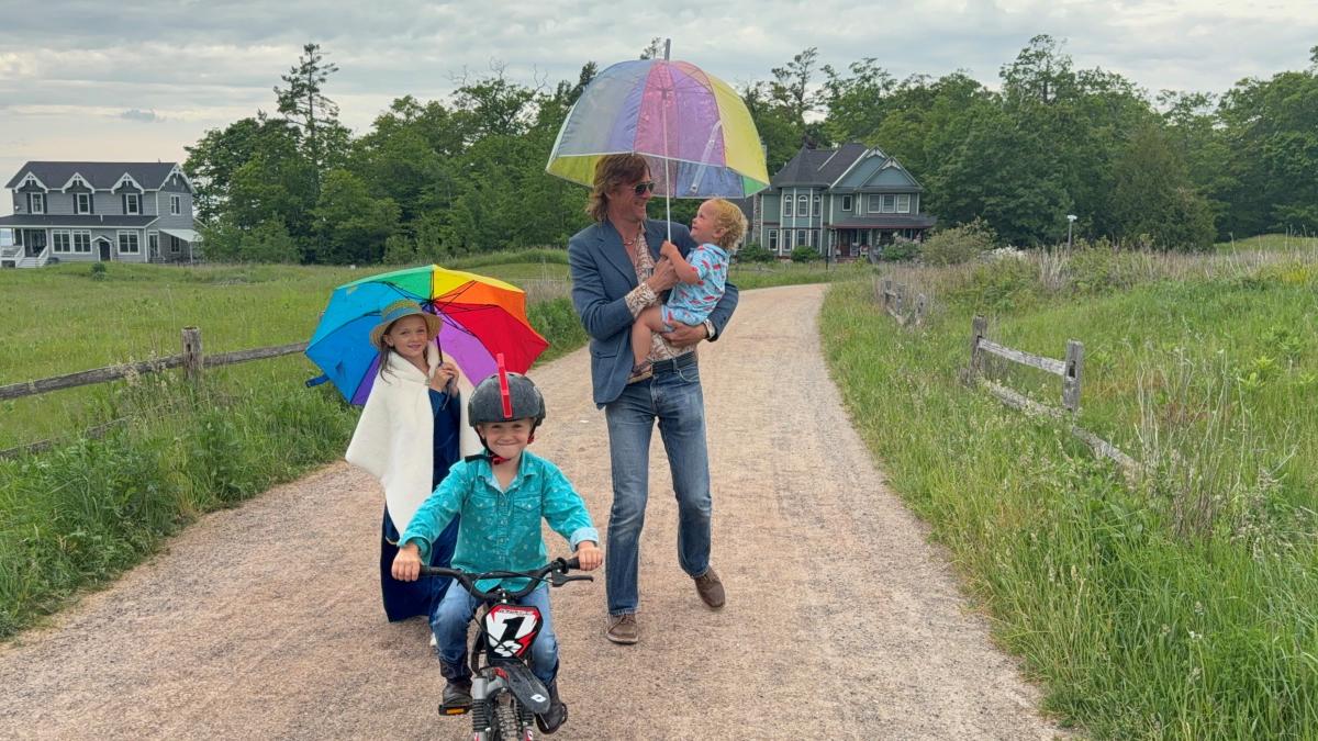 A father and three children travel a dirt path in a residential area of Mackinac Island