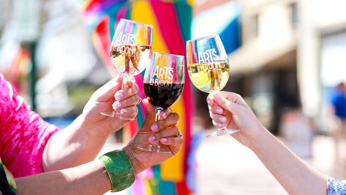 Three wine glasses held by people at an outdoor festival