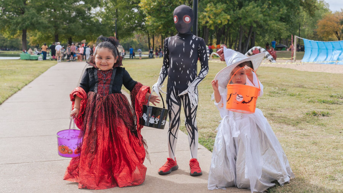 Three children dressed in Halloween costumes with trick or treat bags for candy