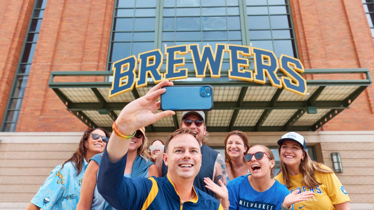 A group of Brewers fans playing a game of corn hole while they tailgate