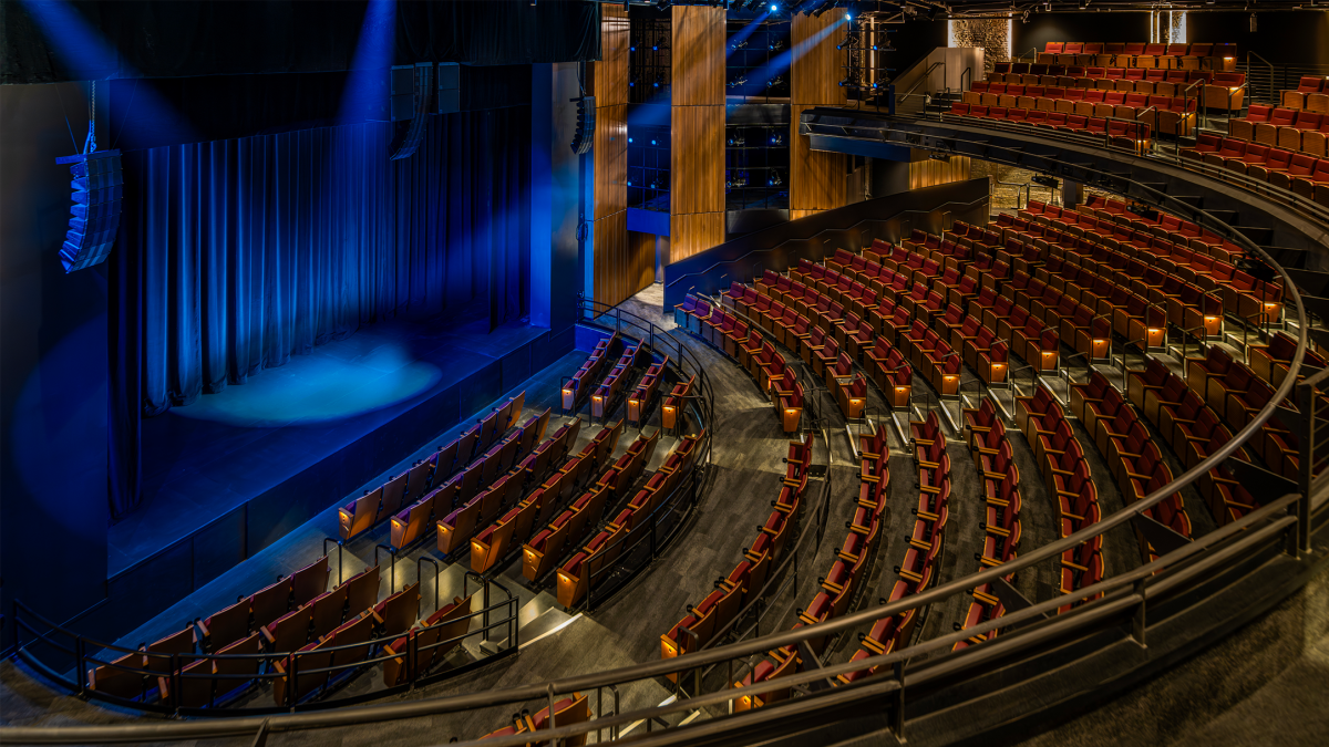 interior of the new Checota Powerhouse at the Milwaukee Rep with curved rows of seats facing a blue-lit stage.