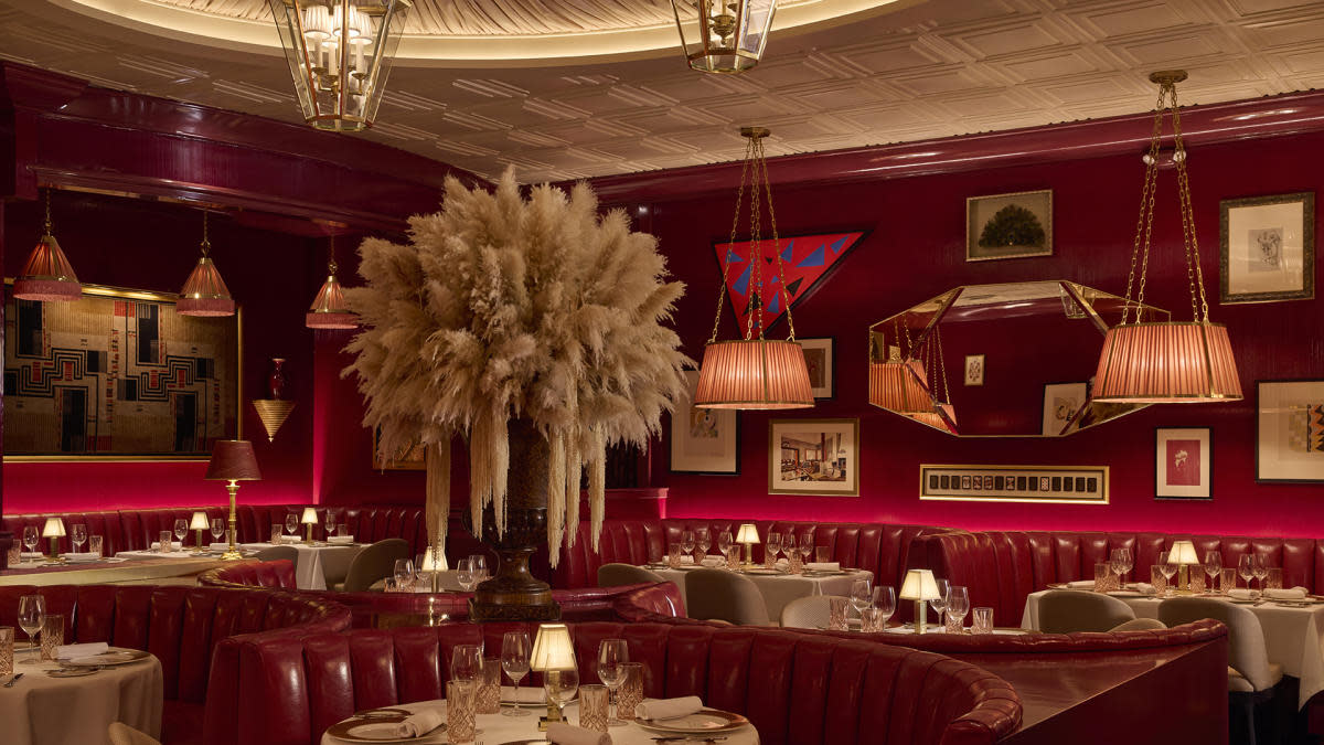Dining room at High Stakes in Milwaukee with red leather booths, white tablecloths, pendant lighting and a large dried floral centerpiece.