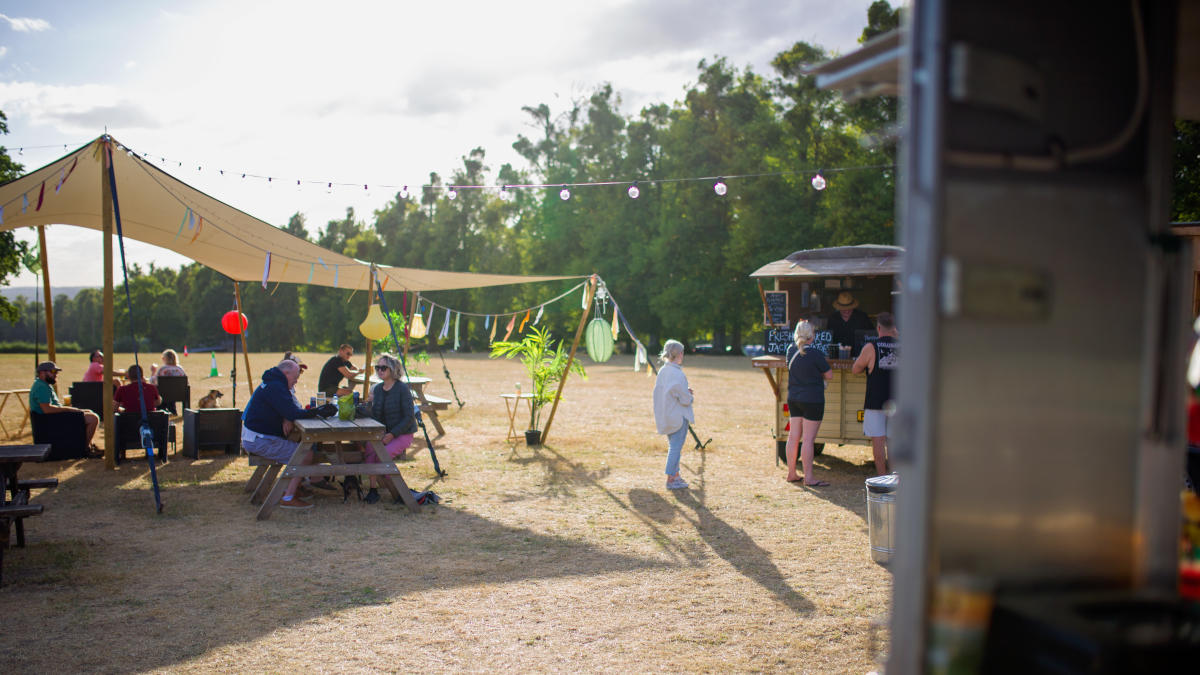 People socialising outside on benches at Harrys Meadow
