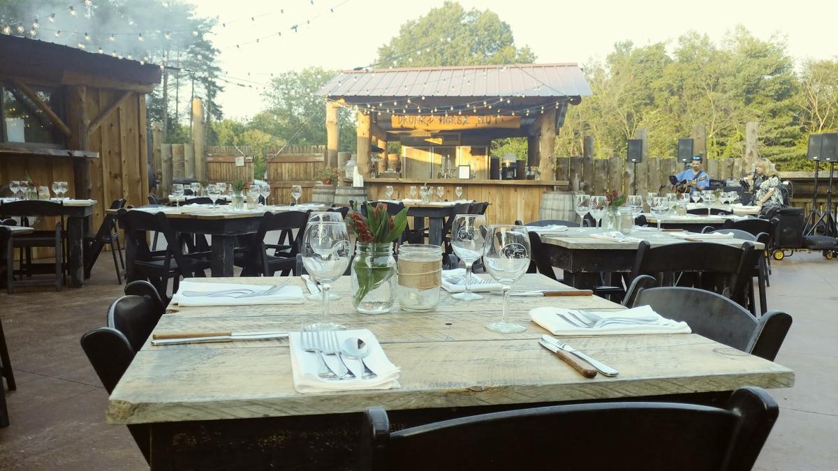 Outdoor dining patio with wine glasses on table and rustic wooden bar