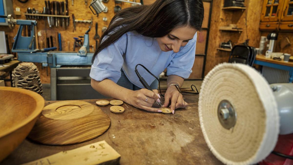 Woman starts imprinting on her handmade wooden pendent