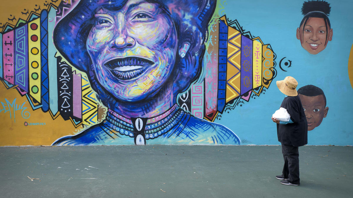 A woman views a large mural of Zora Neale Hurston in Eatonville