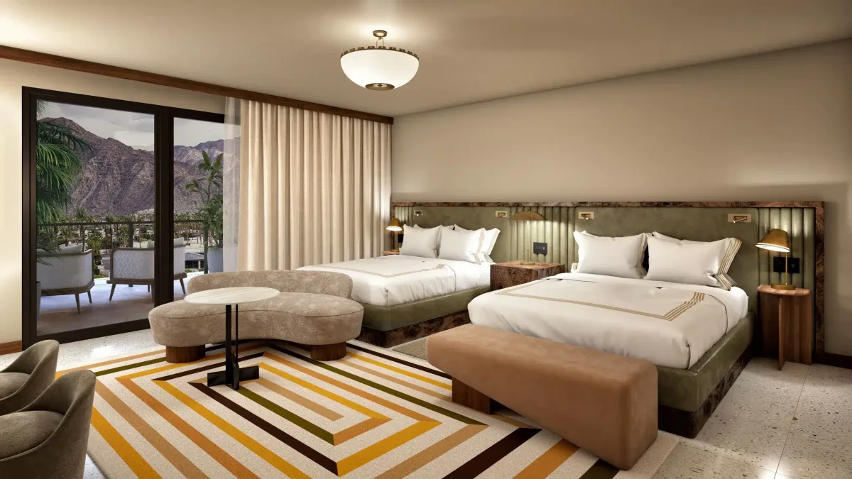 A modern hotel room with two beds featuring white linens, a geometric patterned carpet, contemporary armchairs, and a balcony overlooking a mountainous landscape.