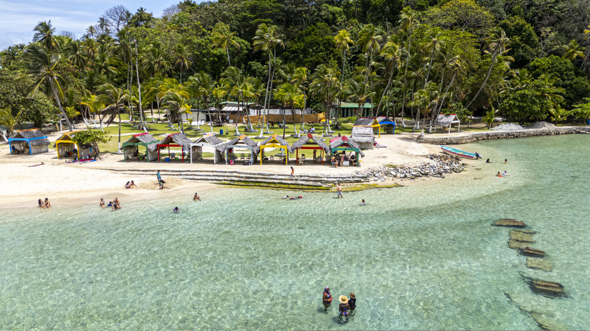 An aerial view captures the lush Isla Mamey in Panama, featuring white sandy beaches fringed with palm trees and turquoise waters.