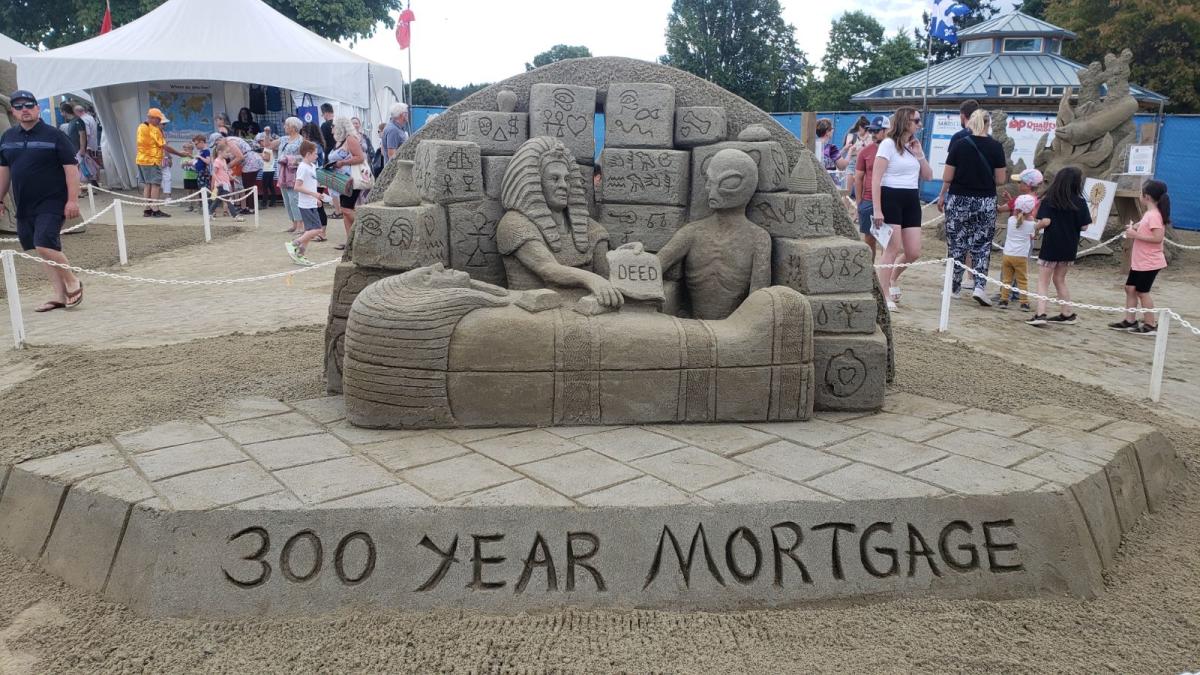 Sand sculpture of an Egyptian man handing money and a "deed" over to an alien. They are standing by a mummy sarcophagus in front of runes. Beneath them is a banner reading "300 year mortgage"