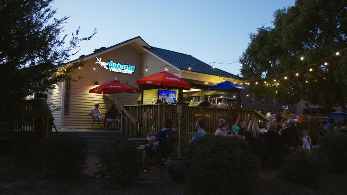 Aviator Brewing Tap House outdoor patio with stringed, handing lights and a lively crowd
