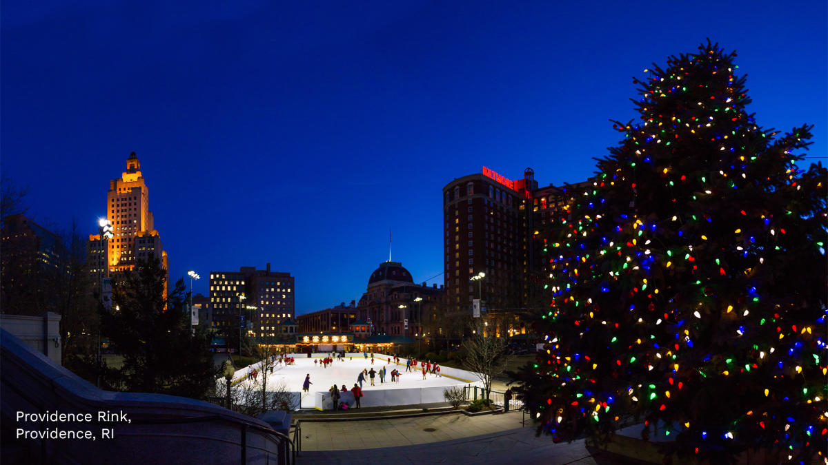 Night at the rink with a Christmas tree and the Providence skyline
