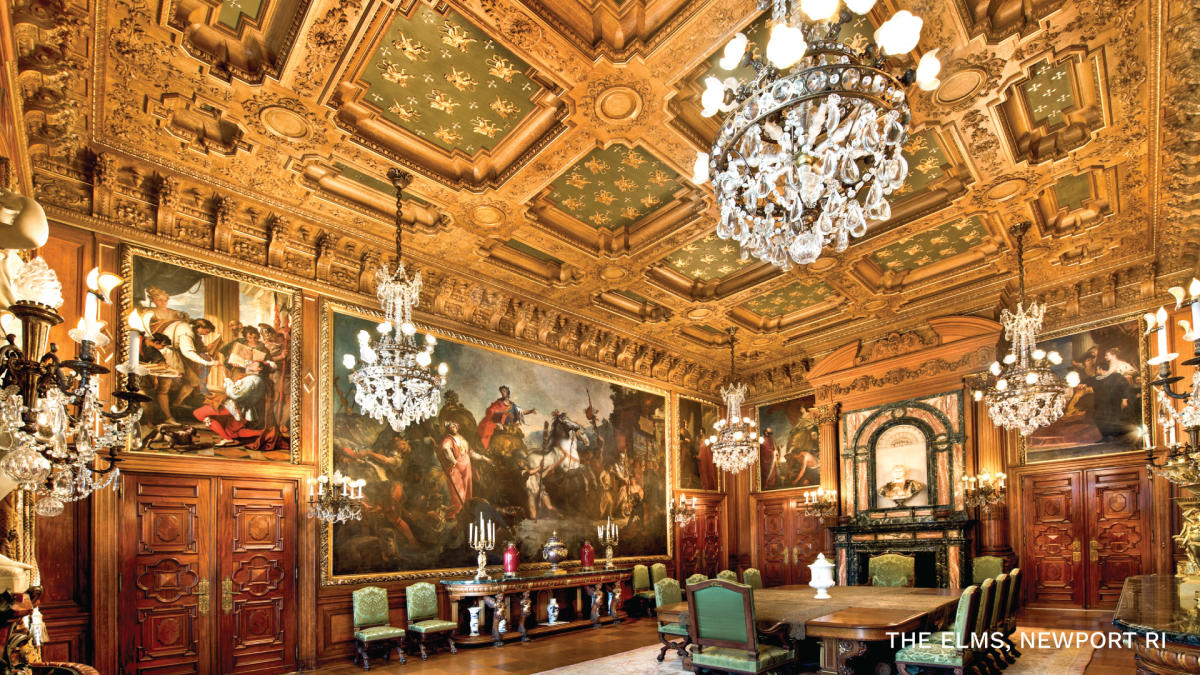 The opulent dining room of the Elms Mansion, with gold paneled ceiling and multiple chandeliers.