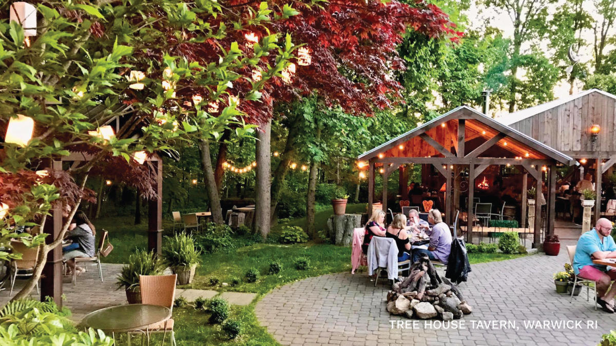 Outdoor dining on a cobblestone patio, with lanterns in the trees.