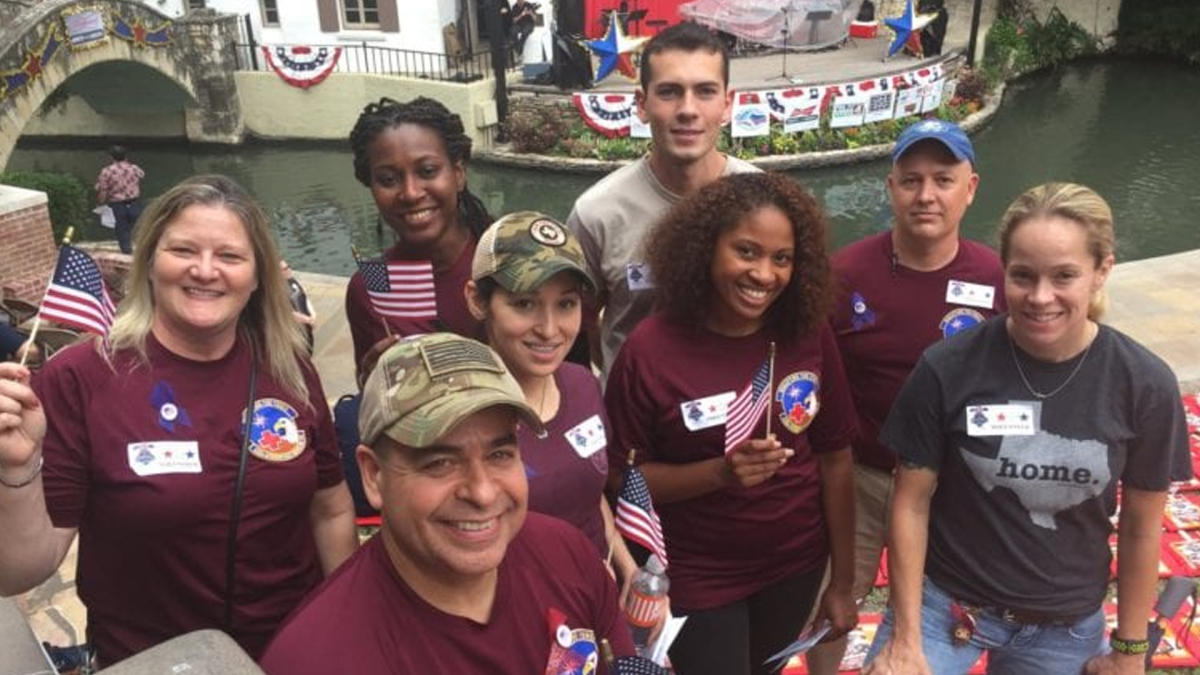 Group of volunteers in maroon shirts holding American flags