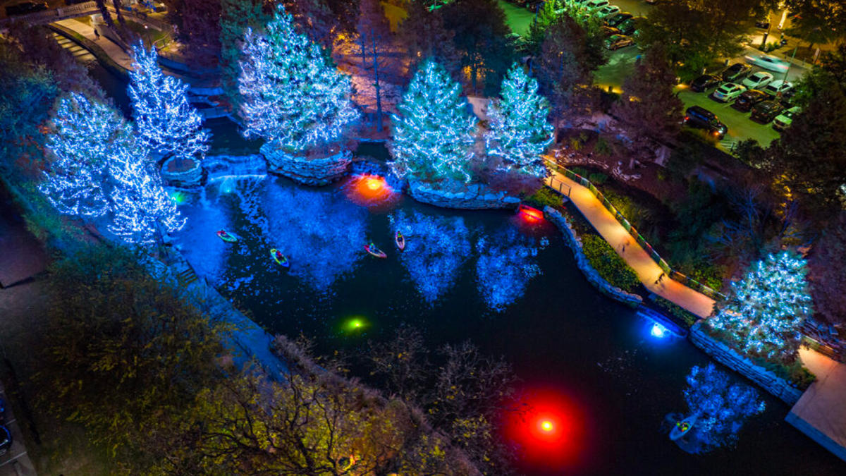 Kayakers on the San Antonio River with trees lit with holiday lights