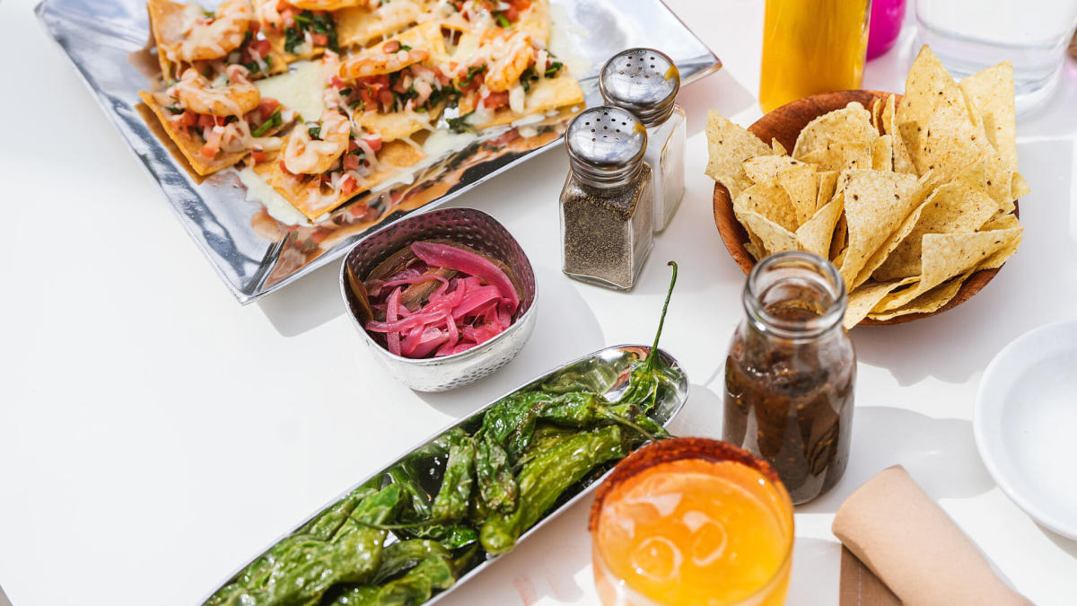 Food spread of peppers, chips, drink, and quesdillas