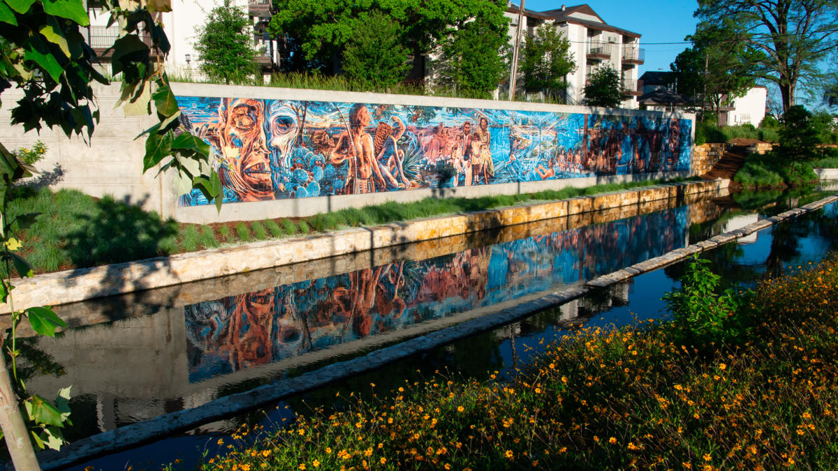 Public art along wall in front of creek