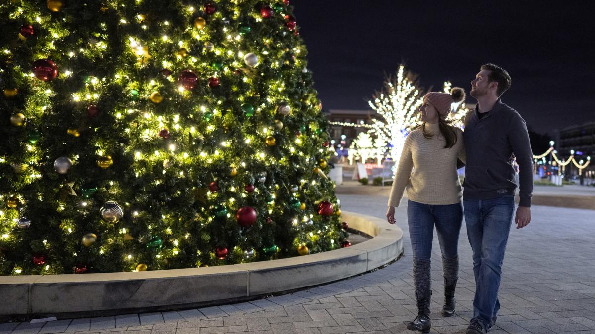 A Couple Walking in Front of a Christmas Tree at Sparkle Sandy Springs