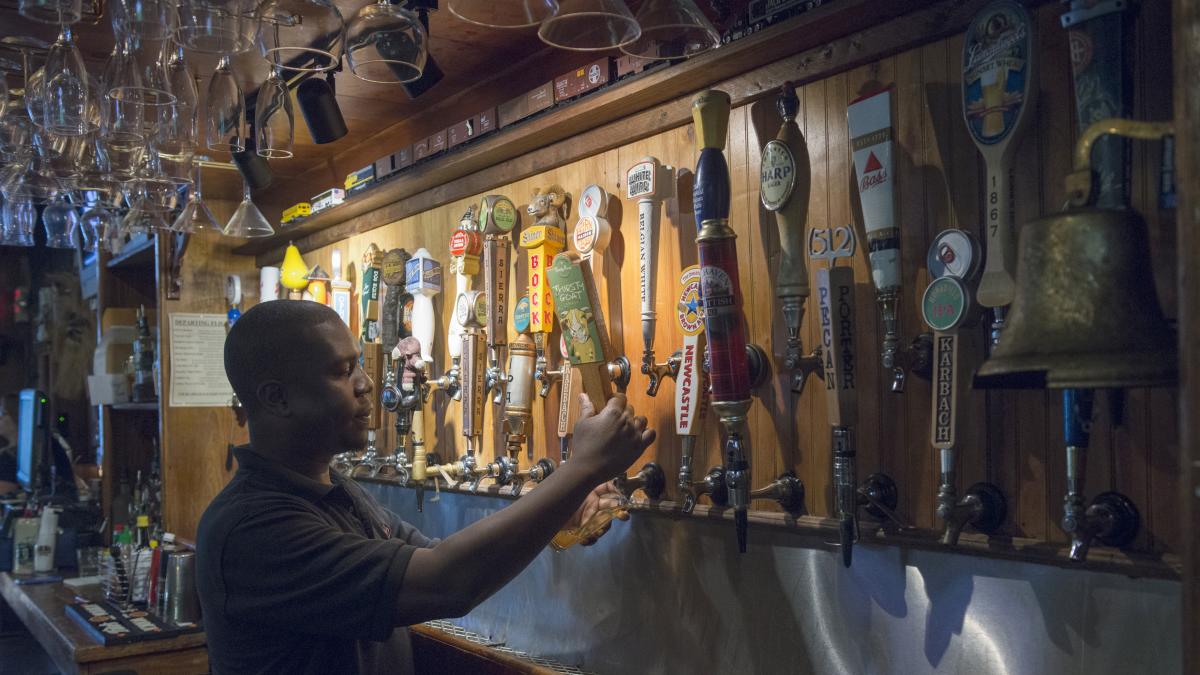 Bartender pouring beer at wall of taps