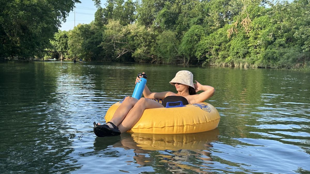 Raeanna floats on a yellow Lion's Club Tube on the San Marcos River