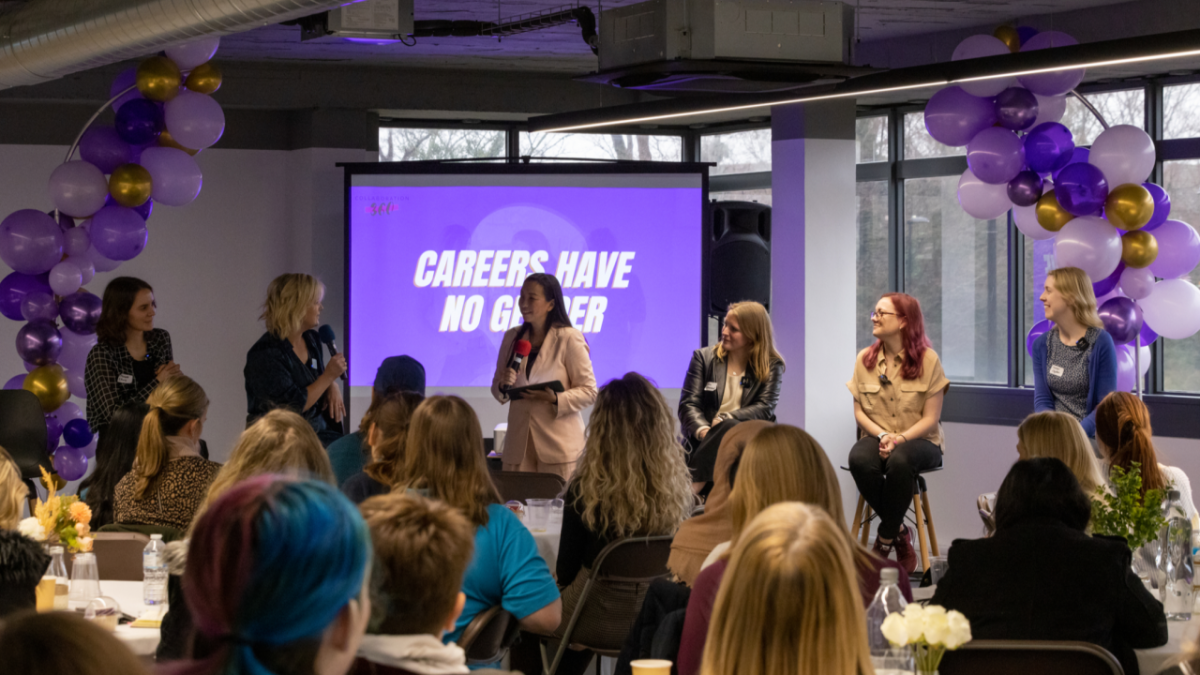 Panel of speakers chatting in front of a group of women at Strong Female Lead event